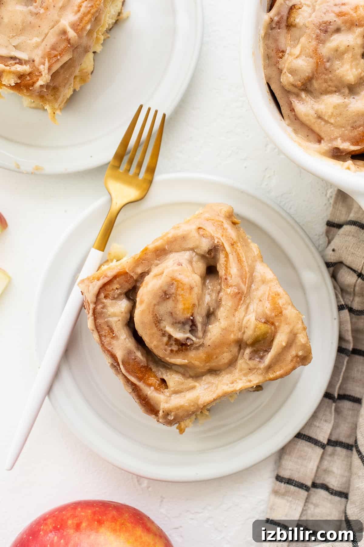 One apple cinnamon roll on a plate with a fork.