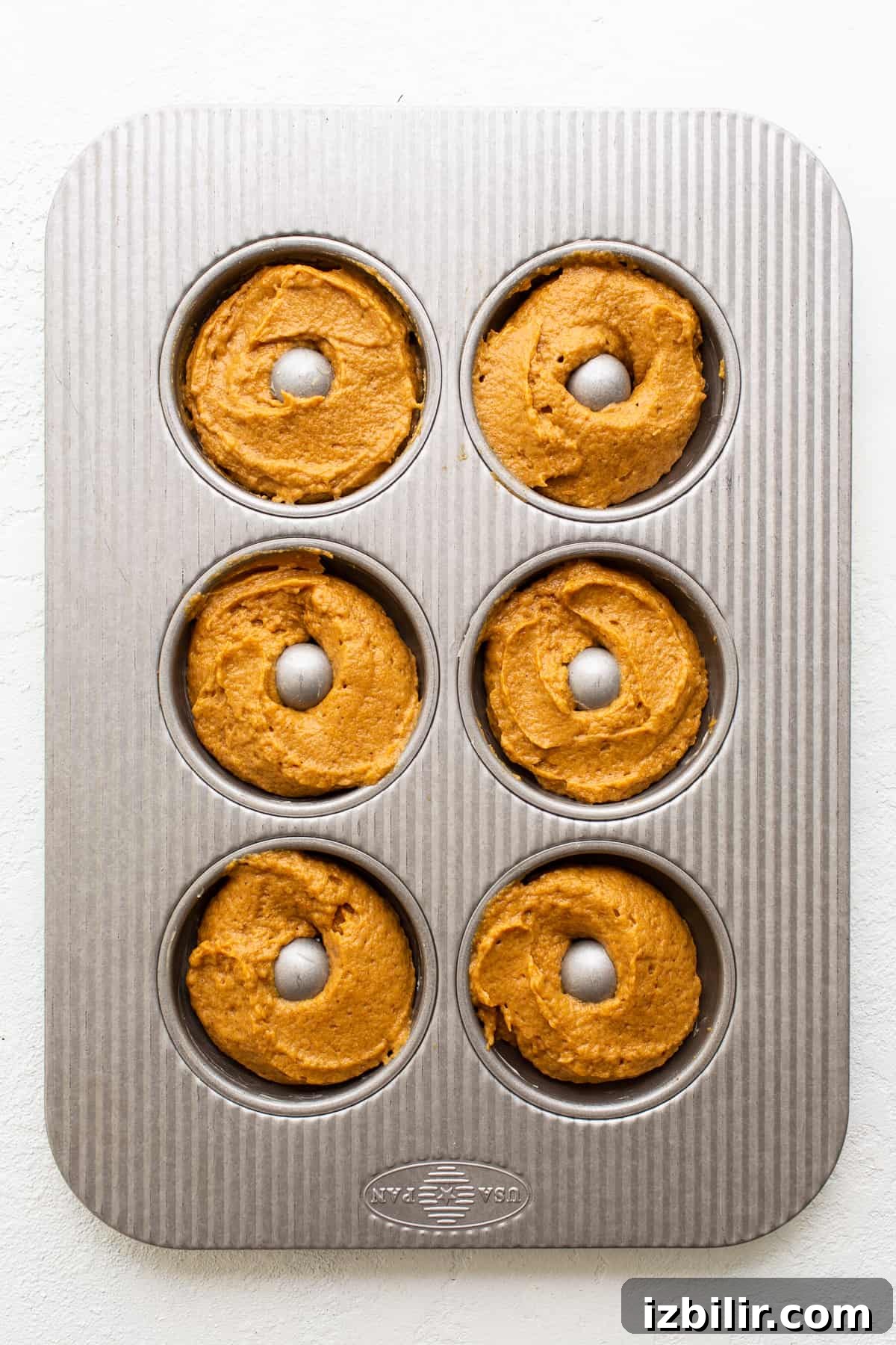 filling donut pan with batter.