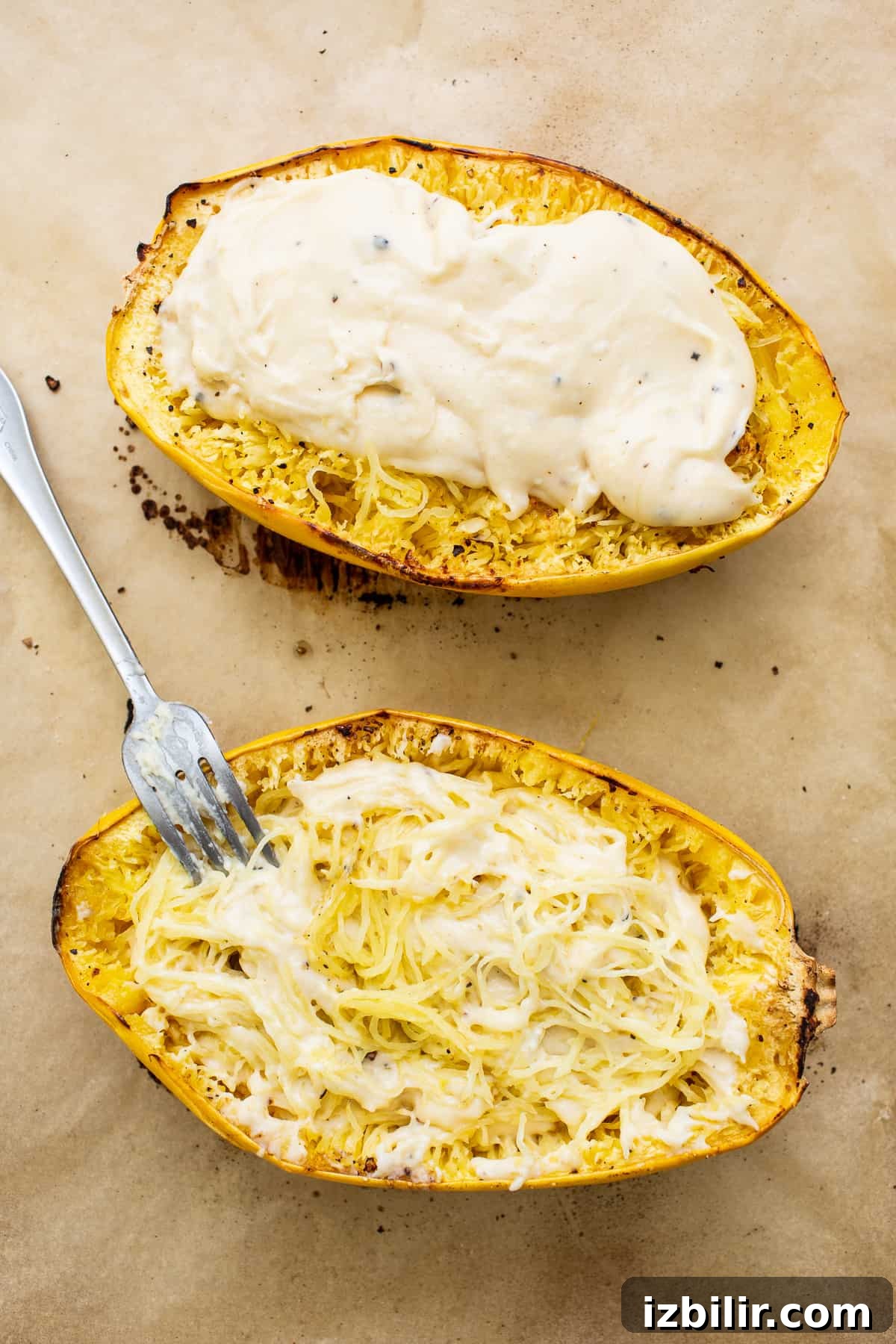 Filled spaghetti squash before broiling Spaghetti squash and cheese sauce on a baking sheet.