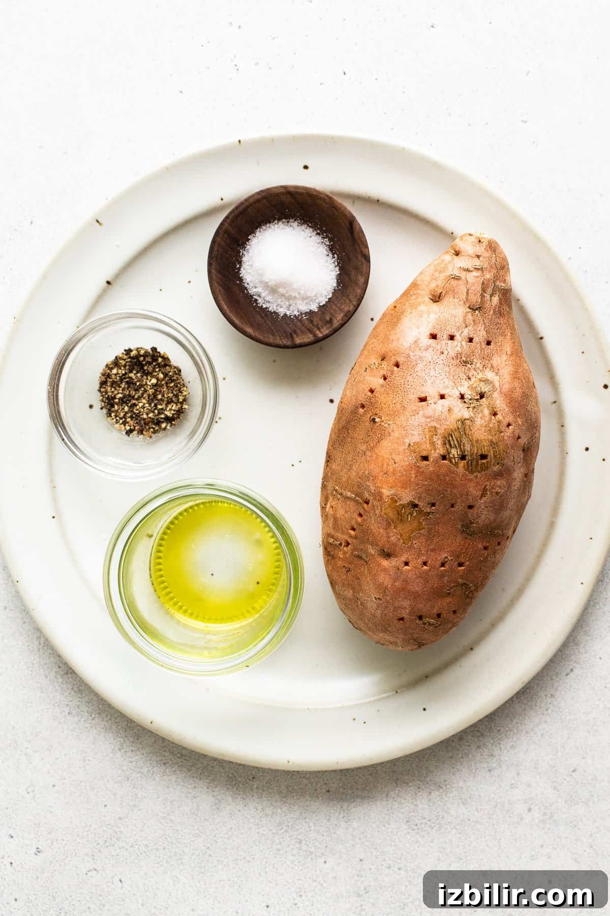 Microwave Sweet Potato to Tender Perfection 4 A sweet potato, salt, pepper, and oil on a plate.