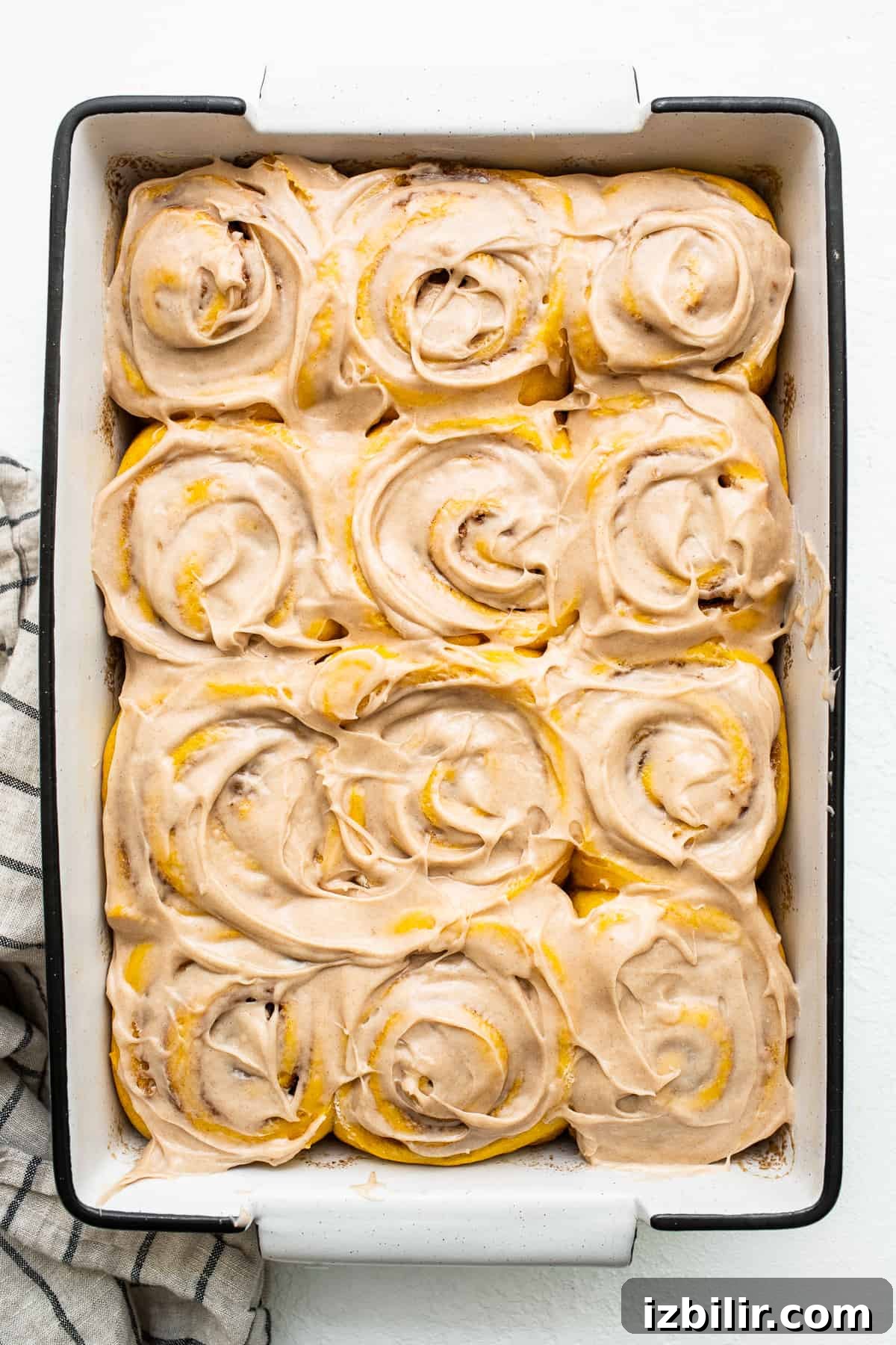 Fluffy Pumpkin Cinnamon Rolls with Cream Cheese Glaze 4 Pumpkin cinnamon rolls topped with a cinnamon cream cheese frosting in a baking dish.