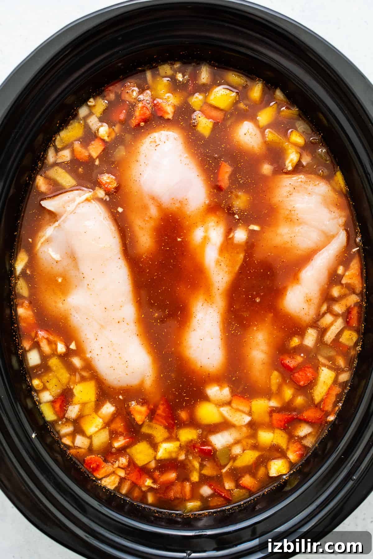 Chicken breasts cooking in the slow cooker. Chicken breasts submerged in soup.