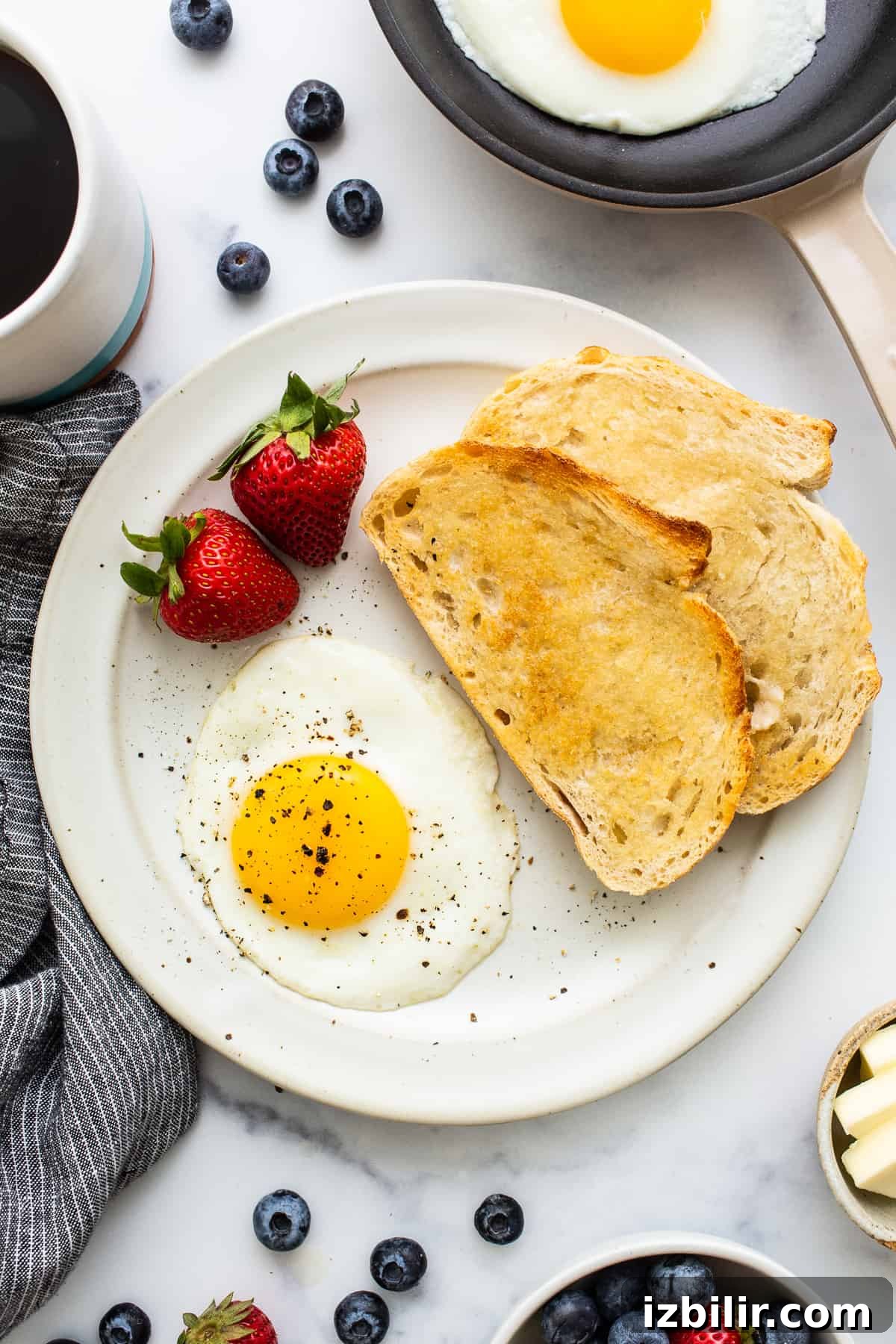 A sunny side up egg on a plate with salt and pepper.