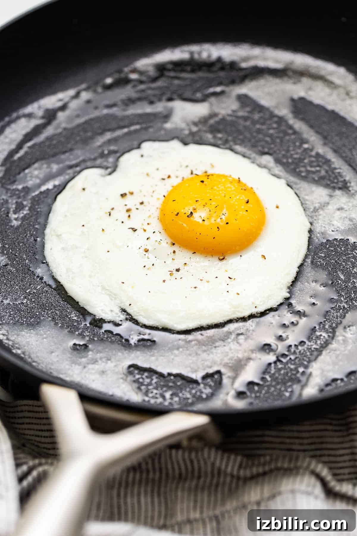 Three sunny side up eggs cooking in a pan.