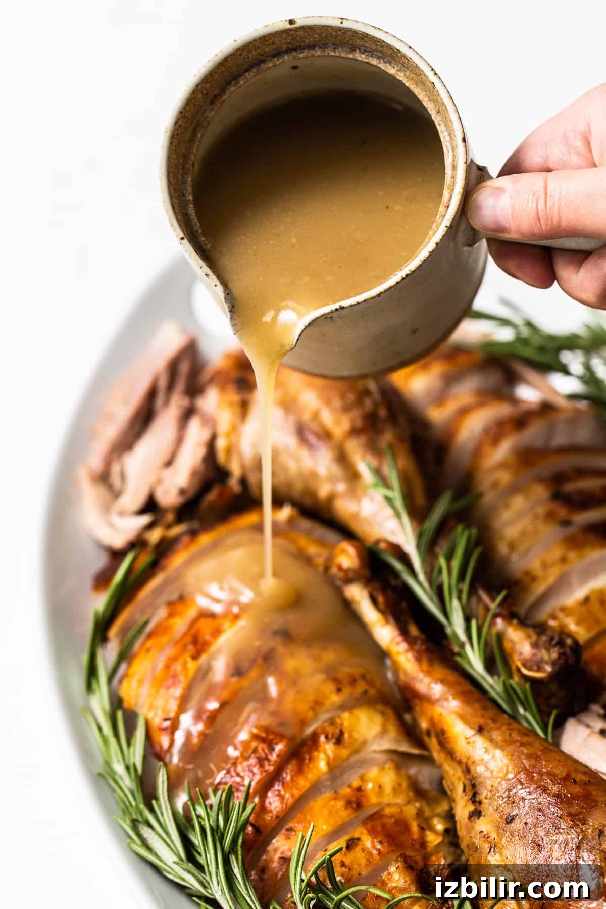 Add this simple turkey gravy to your Thanksgiving menu! It's easily made with turkey drippings, broth and a little bit of cornstarch. Enjoy! Turkey gravy being poured over sliced turkey.