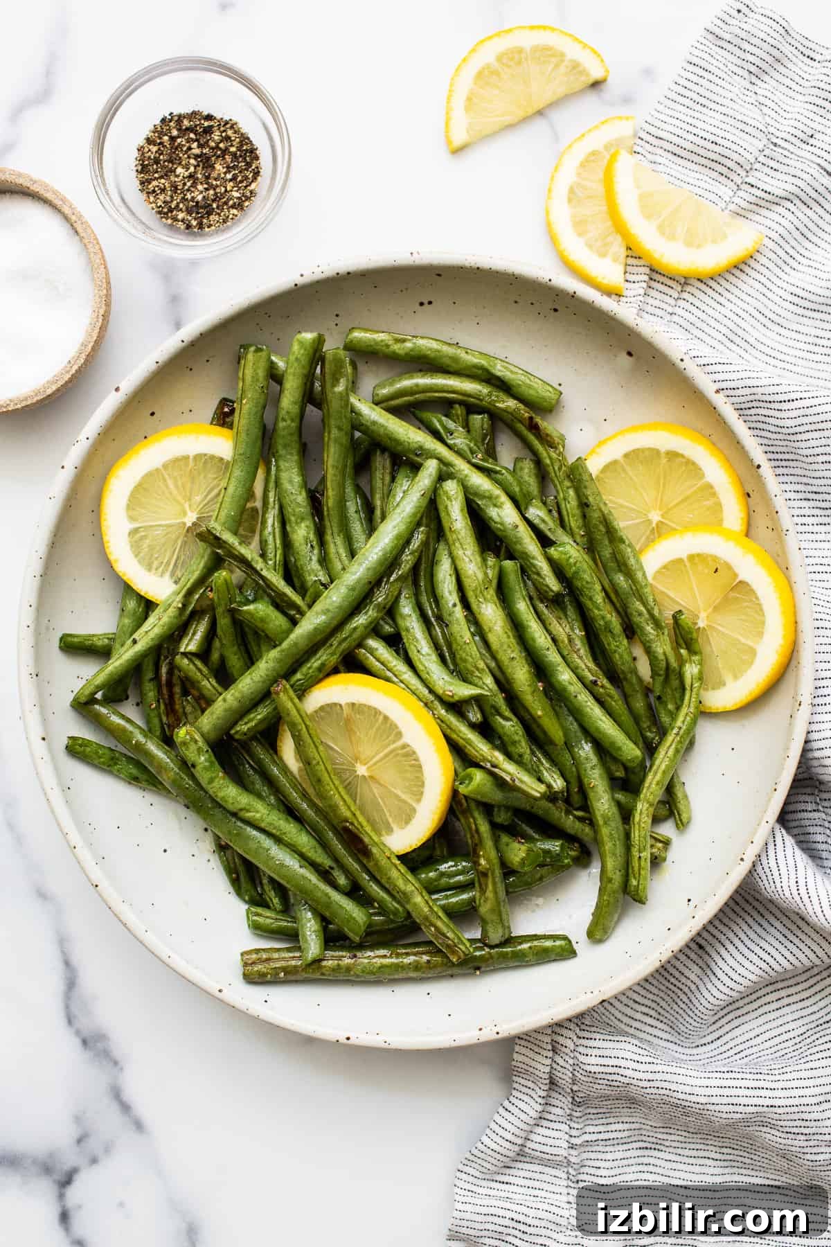 Green beans in a serving bowl with lemon slices.