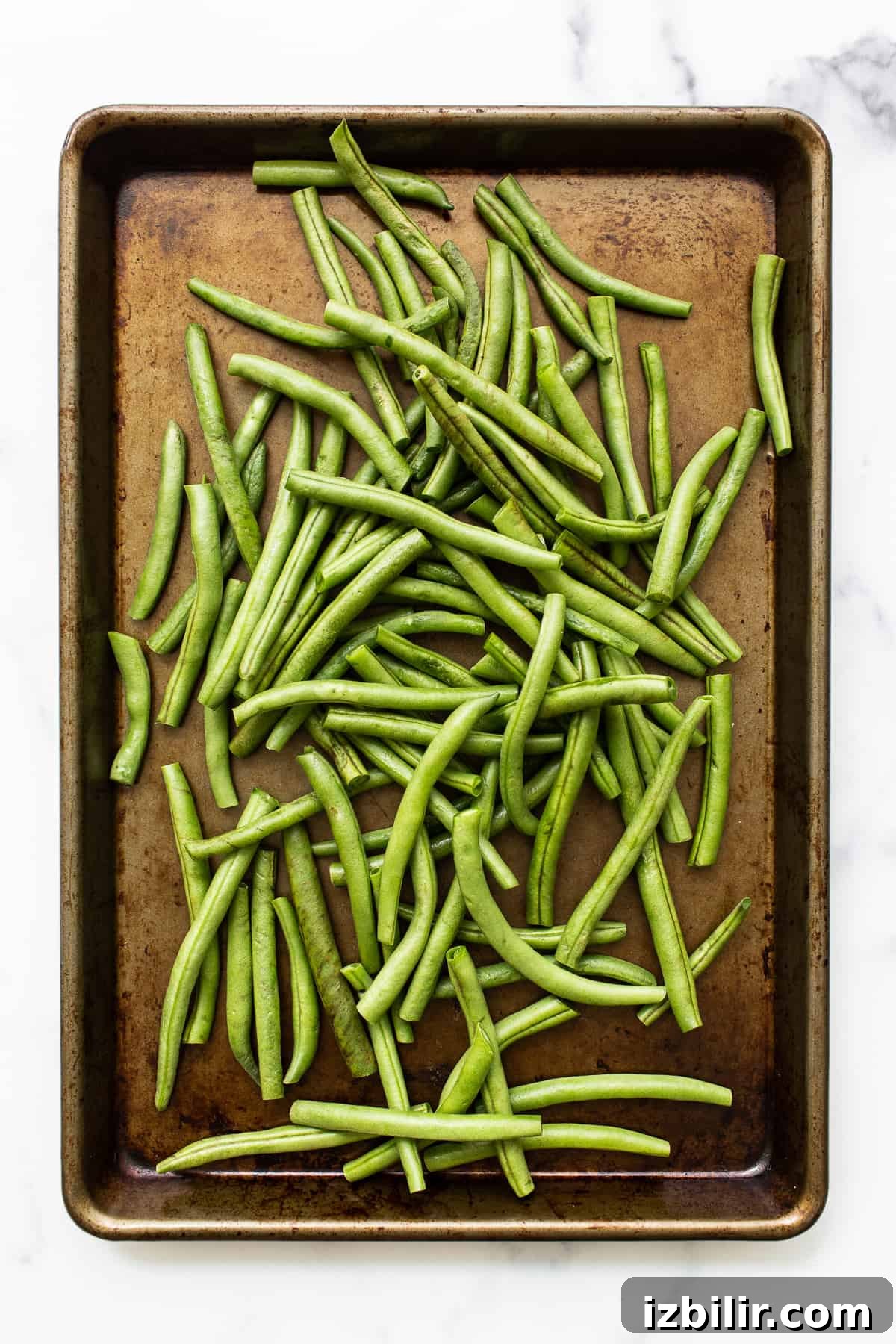 Uncooked green beans on a baking sheet.