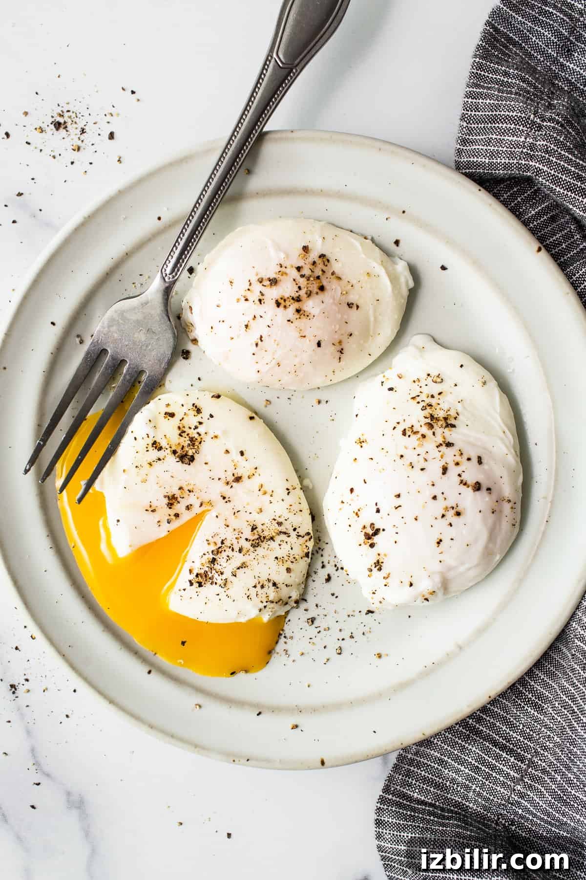 Perfect poached eggs Poached eggs on a plate with a fork.