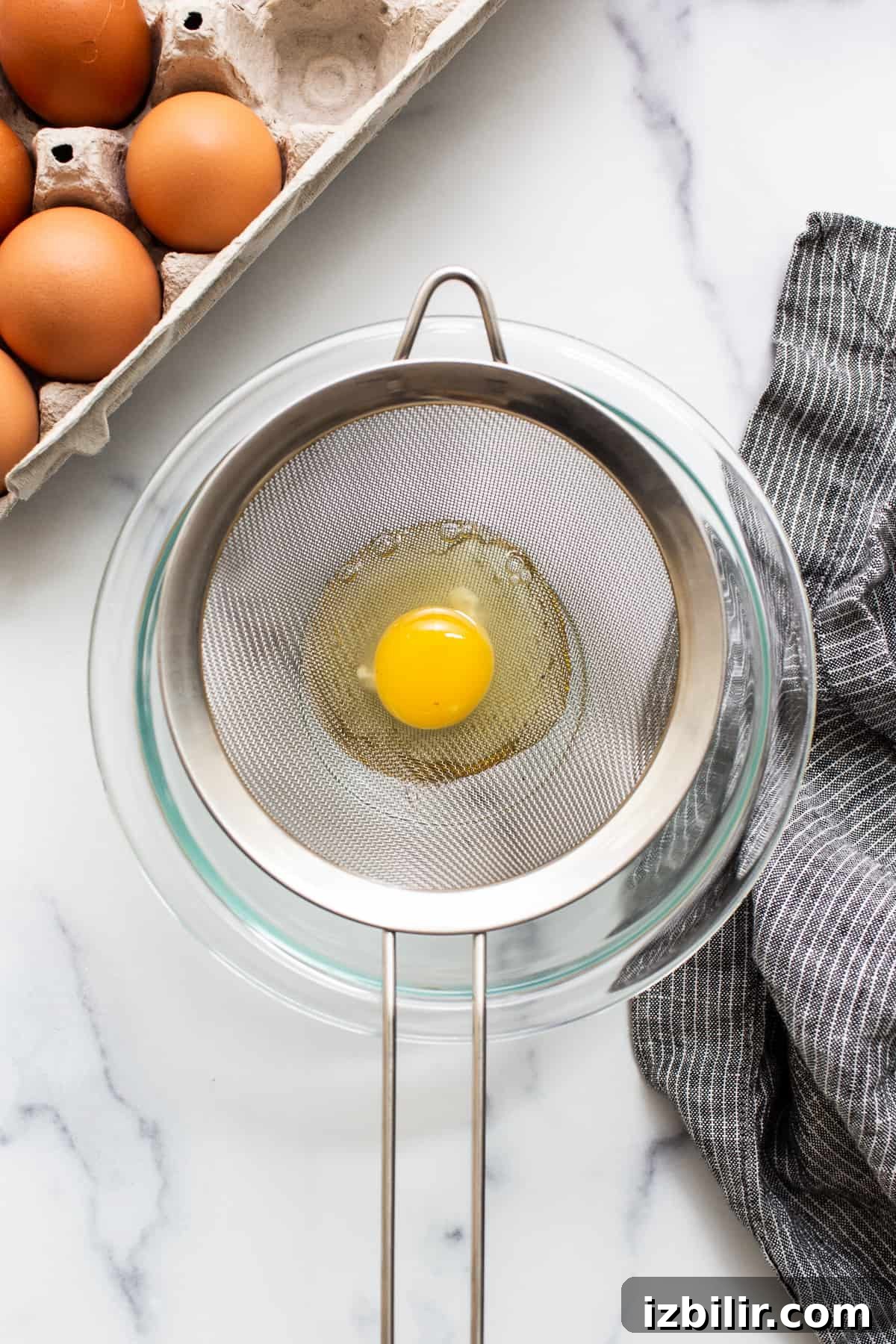 Straining egg whites Raw egg in a mesh strainer.