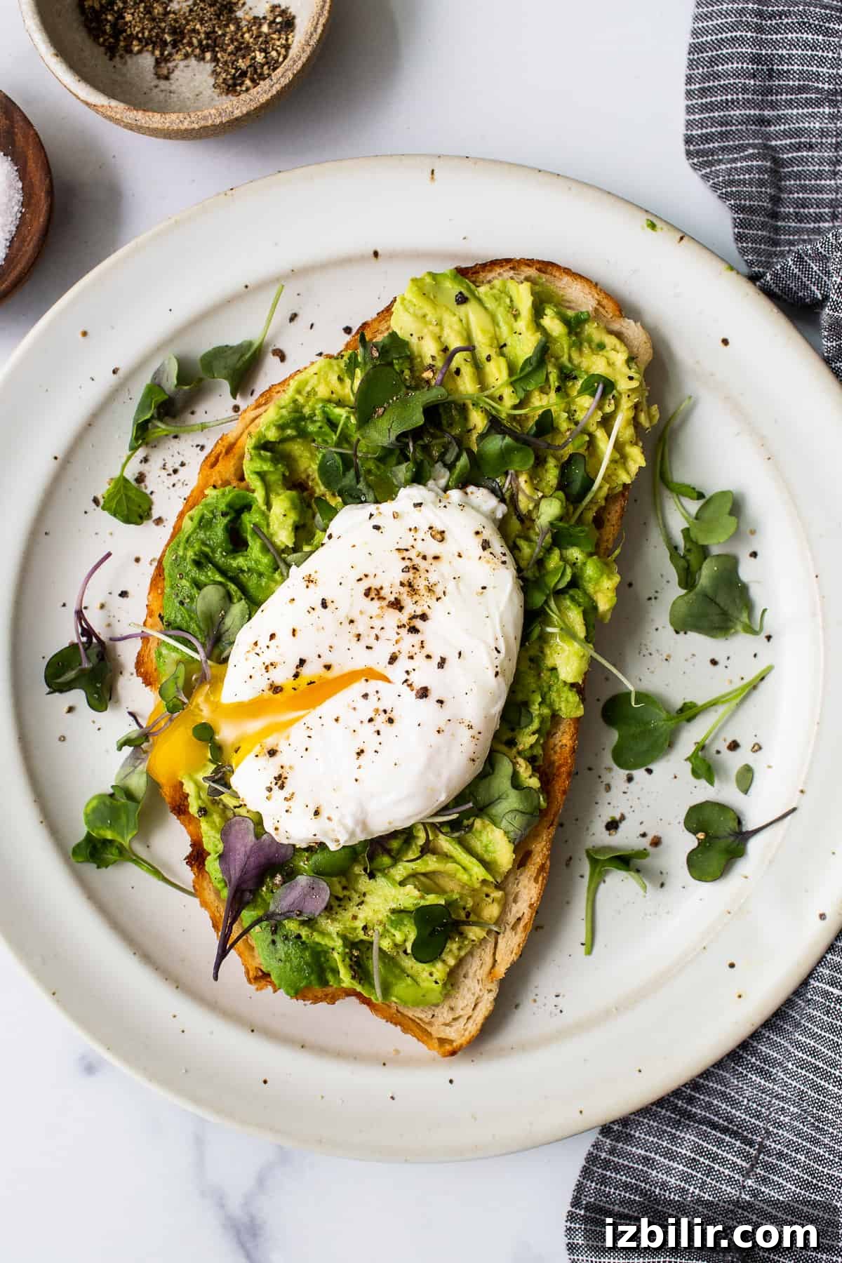 Poached egg on avocado toast with microgreens Poached egg on avocado toast on a plate with microgreens.