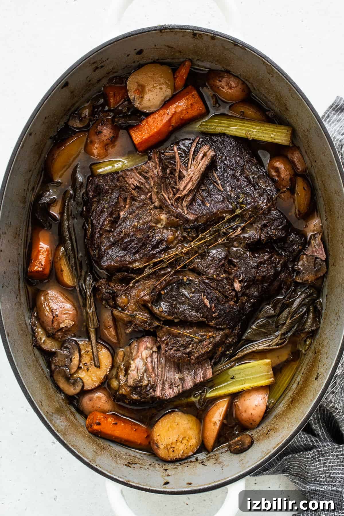 Pot roast resting in the Dutch oven with vegetables. Cooked pot roast in a dutch oven surrounded by veggies.