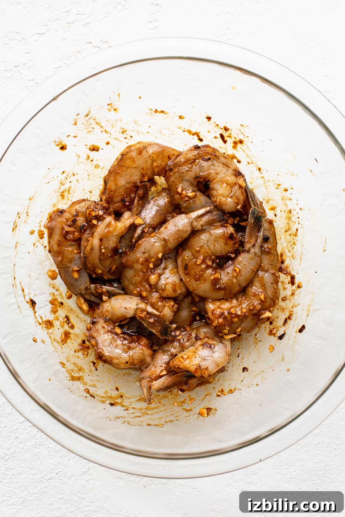 Raw shrimp in a bowl with a marinade.