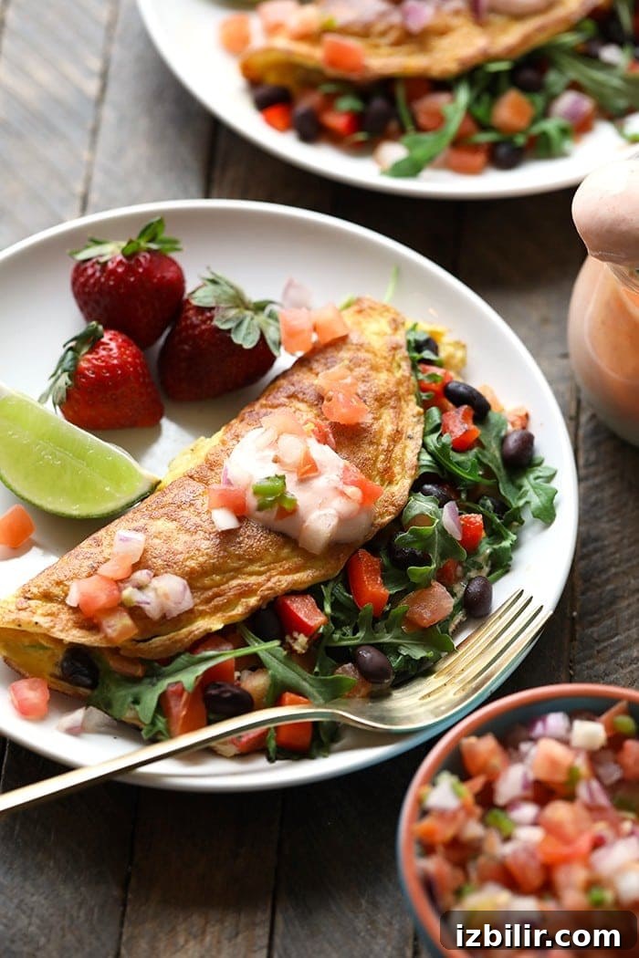 15+ Egg Breakfast Recipes to Elevate Your Morning 19 a plate of veggie omelette with black beans and strawberries.