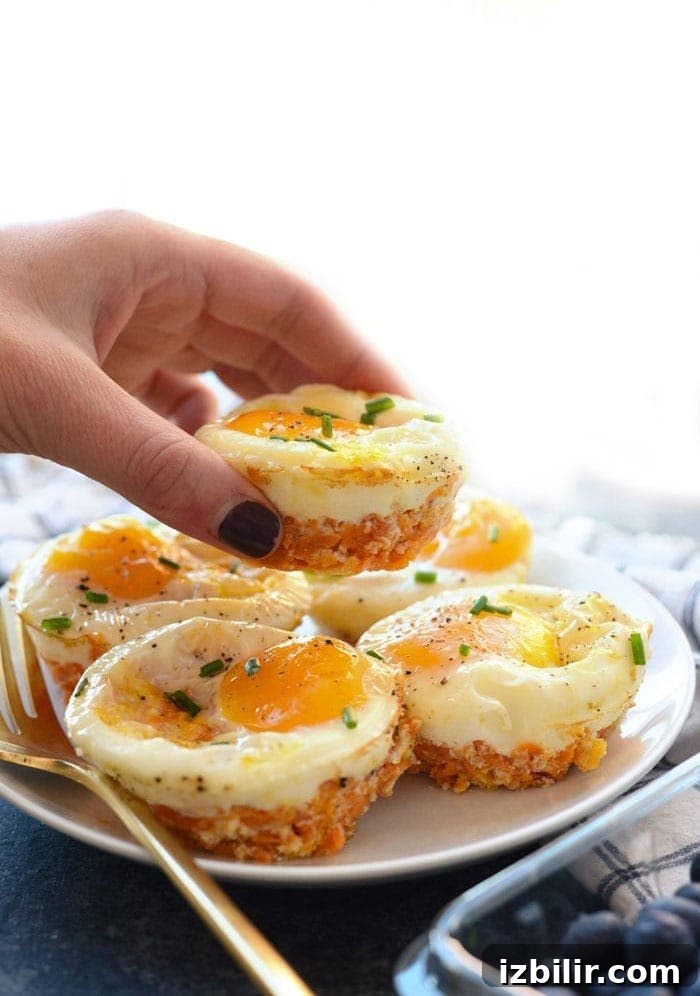 15+ Egg Breakfast Recipes to Elevate Your Morning 9 A person holding up a plate of Sweet Potato Hash Egg Cups on a plate.