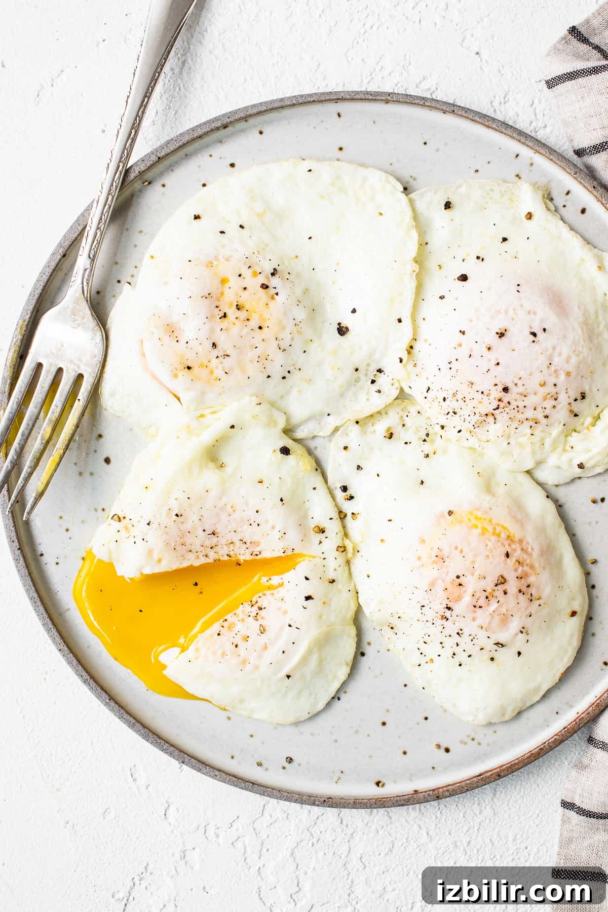 This over easy eggs recipe uses a simple technique that creates the perfect runny yolk and fluffy egg whites every time. Over easy eggs on a plate.