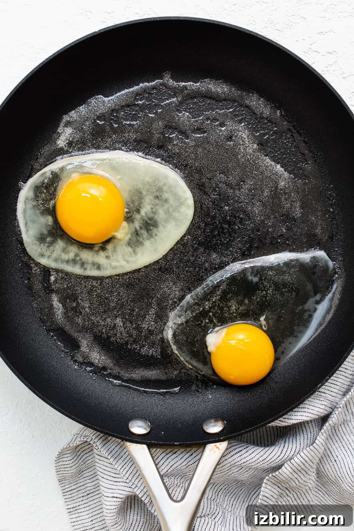 Over hard eggs cooking in a skillet.