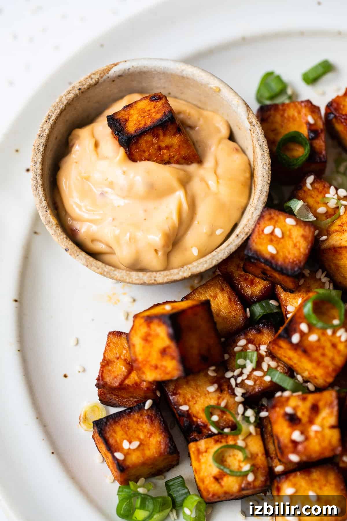 A piece of tofu in a spicy dipping sauce.