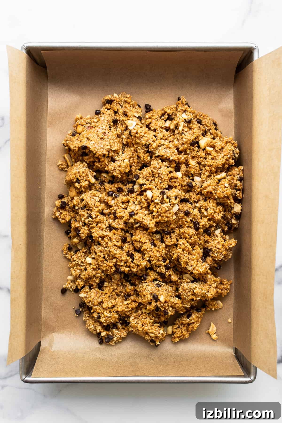 No-bake peanut butter bar mixture pressed into a baking pan. No bake peanut butter bar batter in a baking sheet.