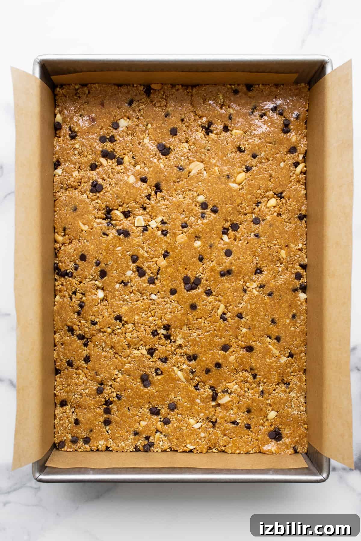 Peanut butter bars pressed into a pan before freezing. No bake peanut butter bars pressed into a cake pan.
