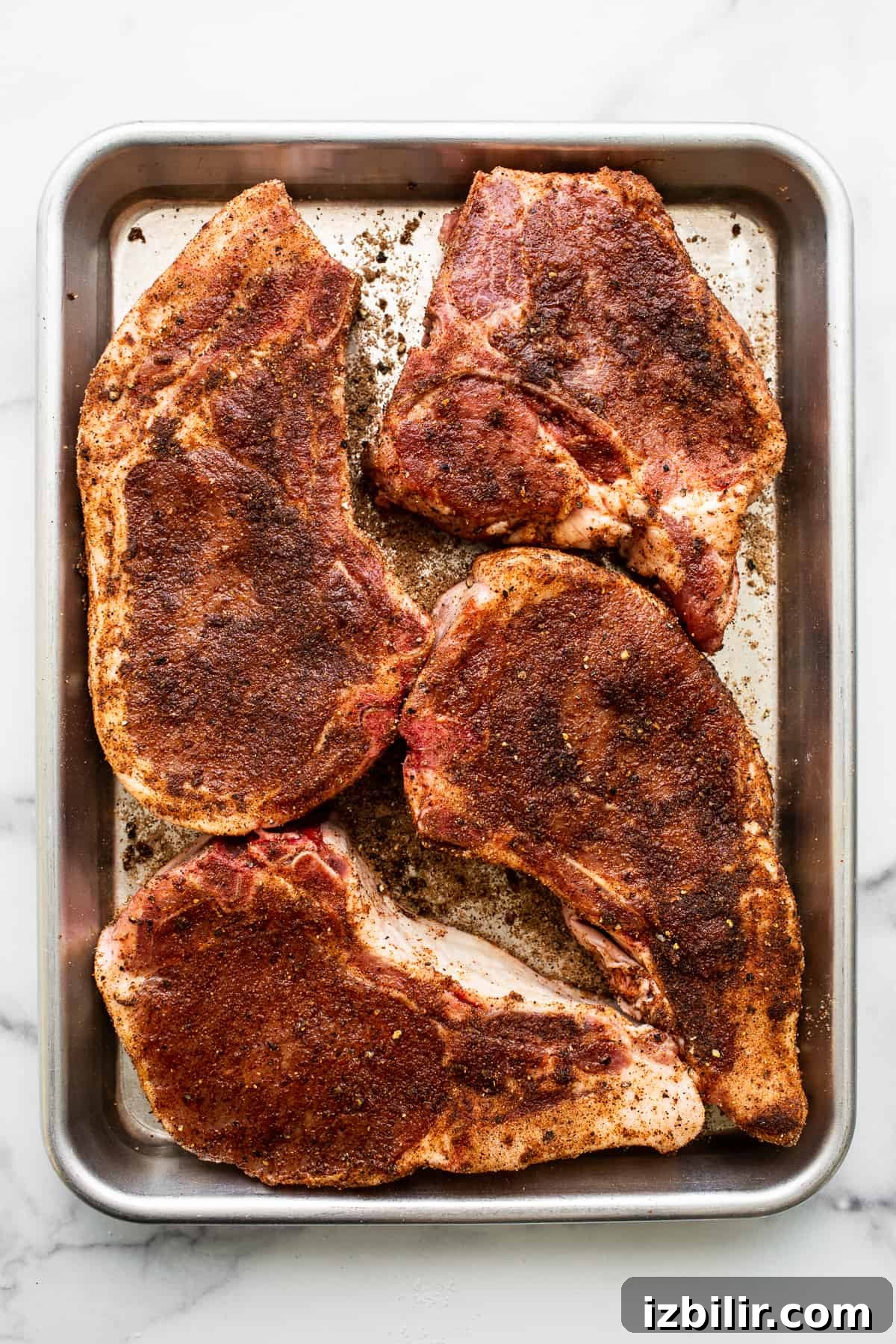 Raw pork chops on a baking sheet.