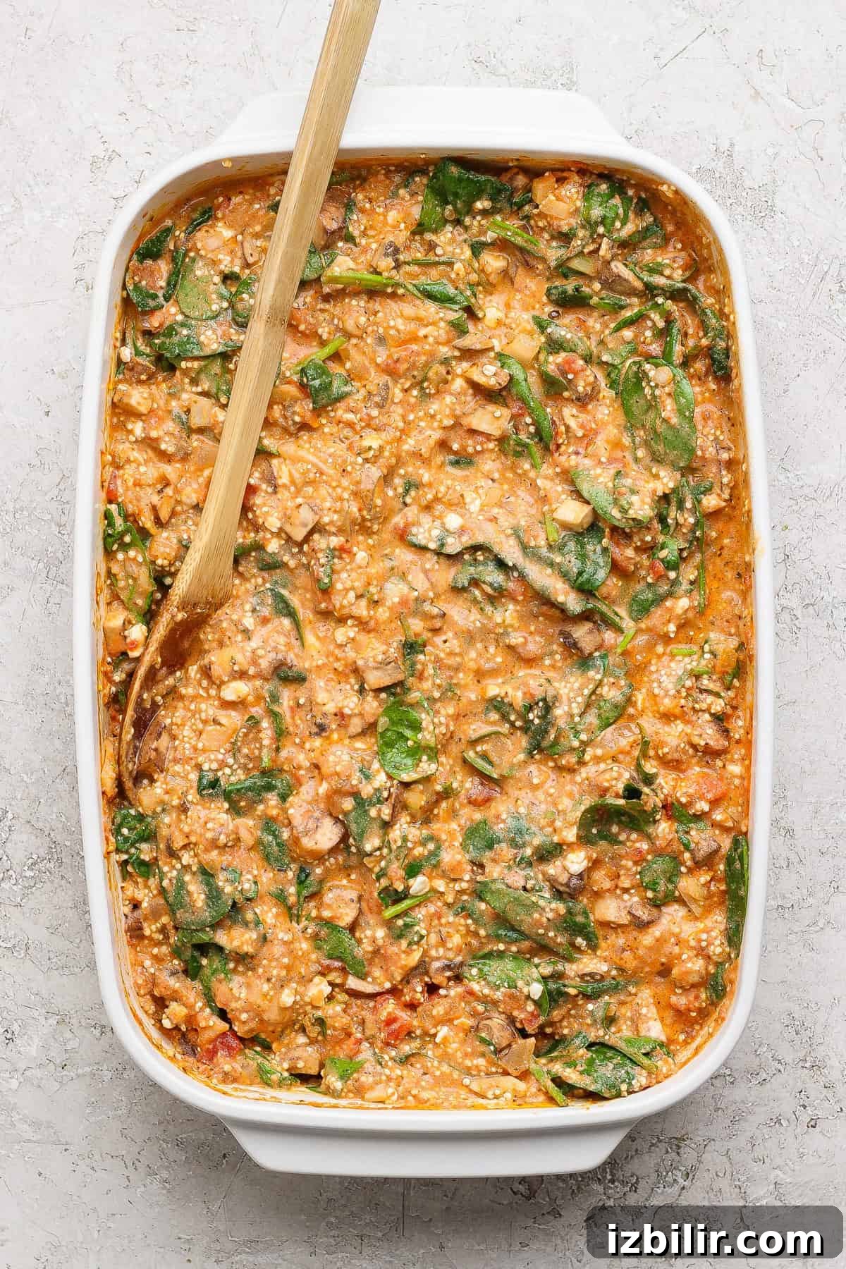 Spinach and Quinoa Lasagna Casserole Recipe 5 Stirring quinoa and spinach filling with a wooden spoon in a baking dish