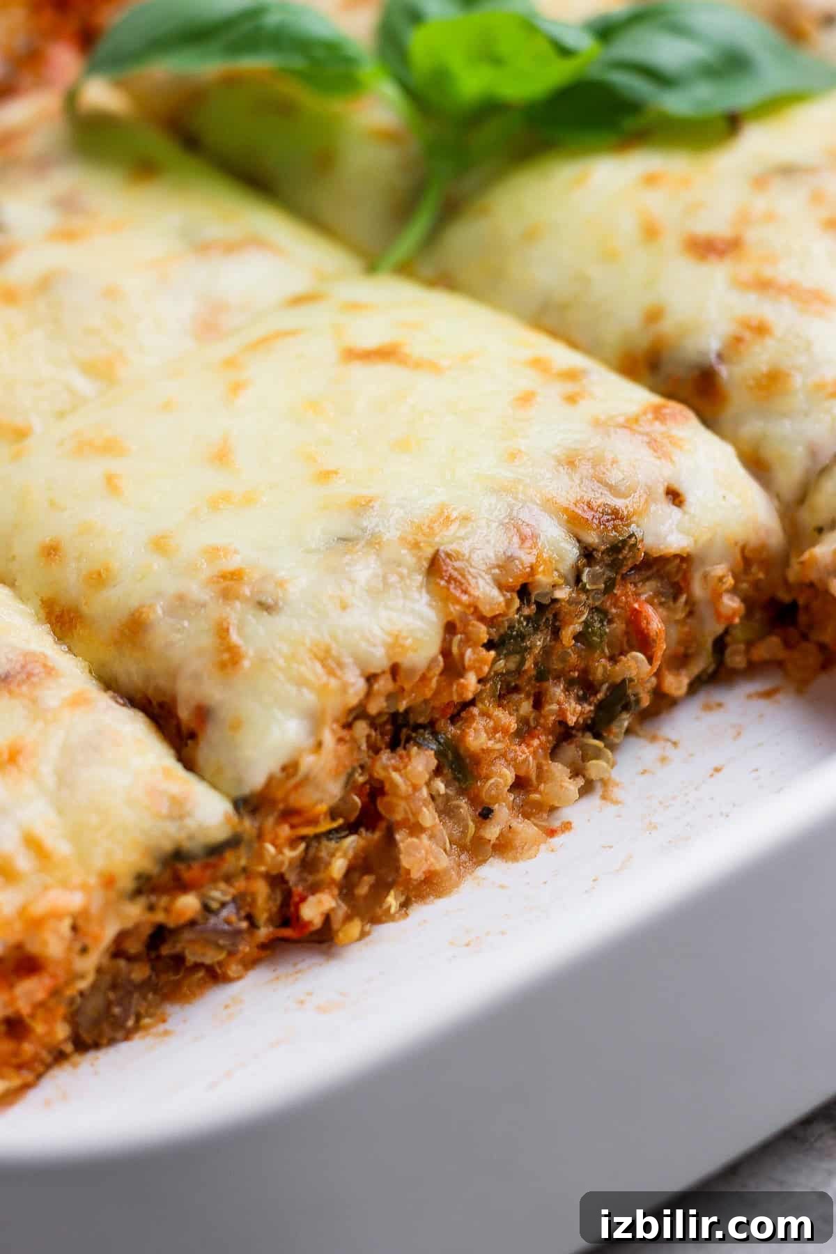 Spinach and Quinoa Lasagna Casserole Recipe 7 Close-up of spinach quinoa lasagna casserole slices in a white baking dish topped with melted cheese and basil