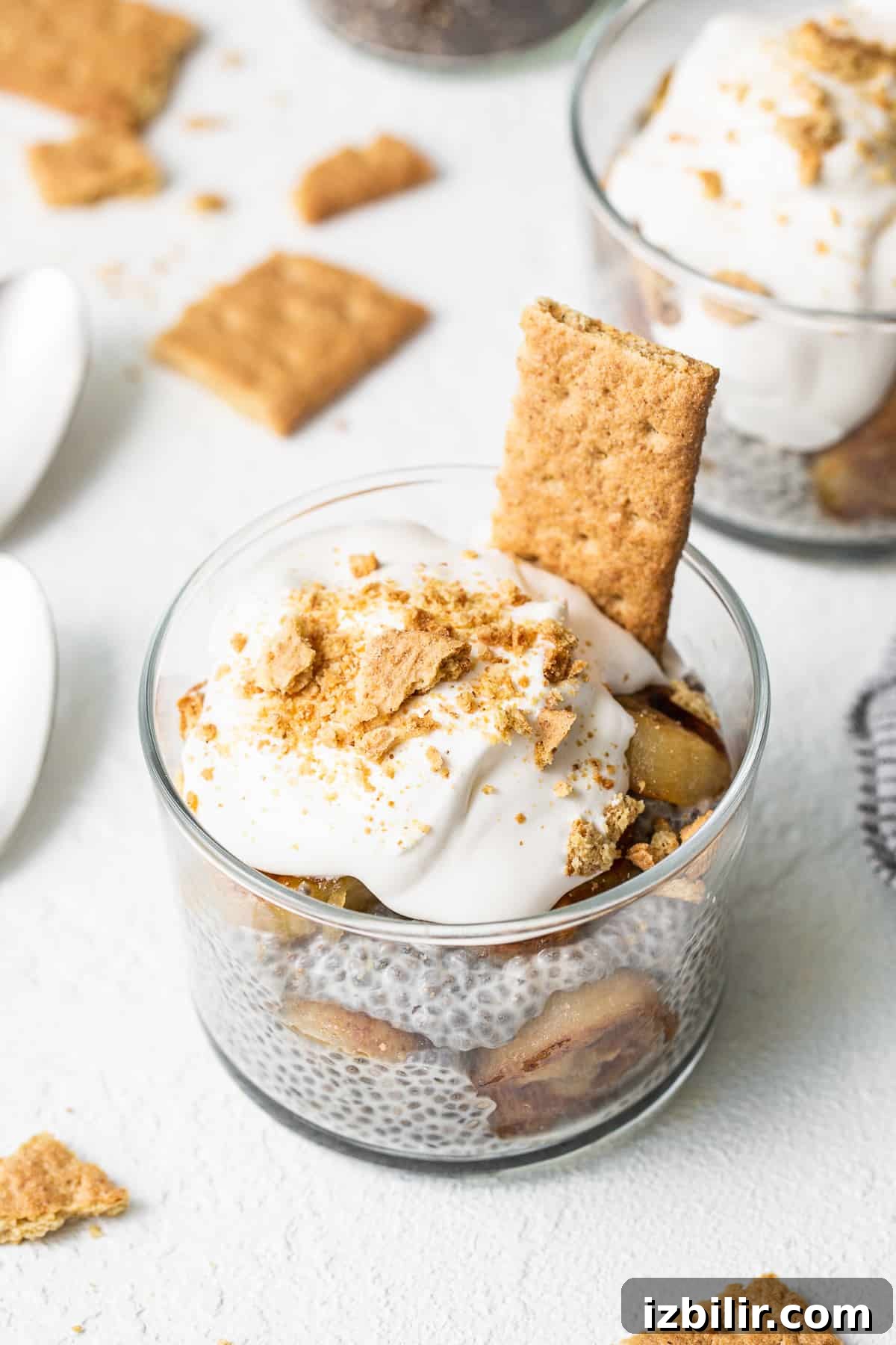 A layered banana cream pie chia seed pudding topped with graham cracker crumbs. Banana cream pie chia seed pudding in a glass topped with graham crackers.