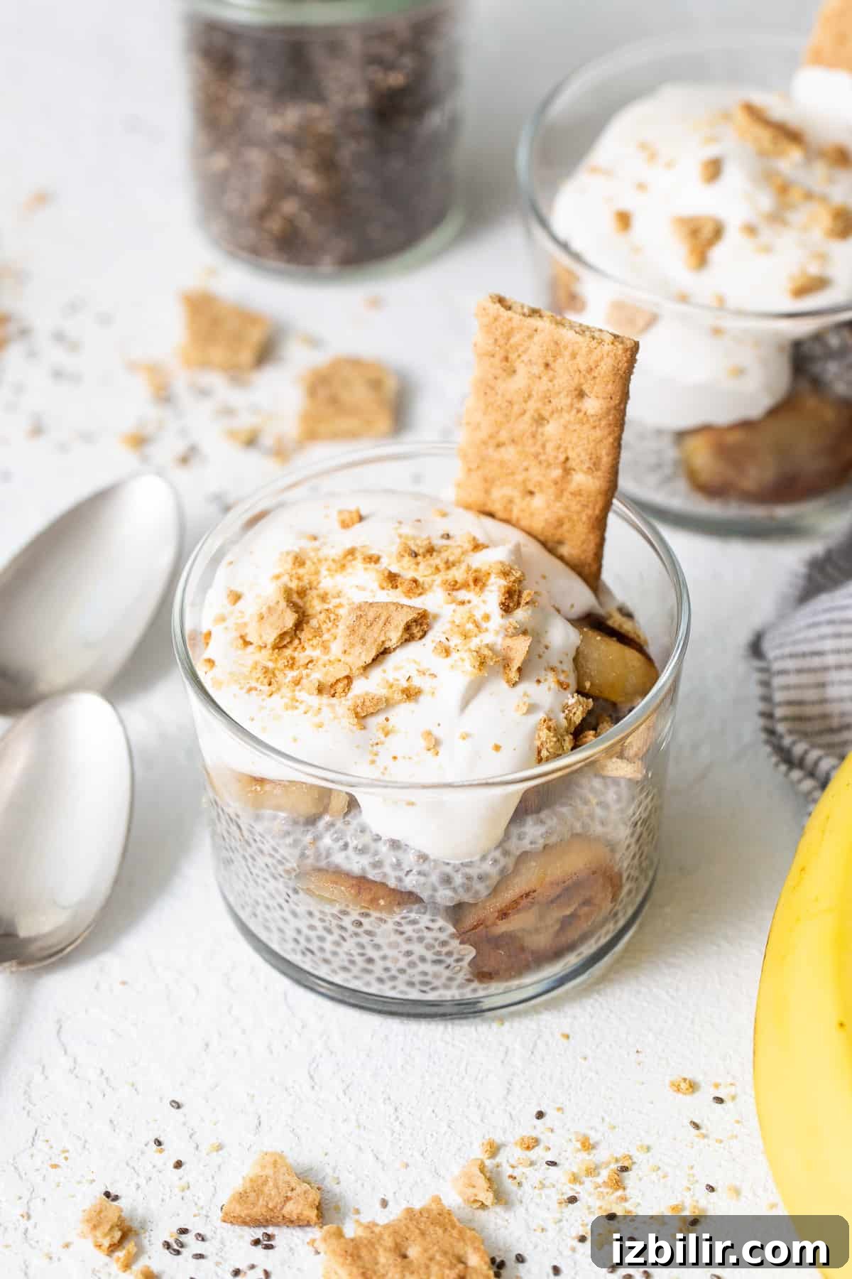 Banana cream pie chia seed pudding ready to enjoy. Banana cream pie chia seed pudding in a glass topped with whipped cream and graham crackers.