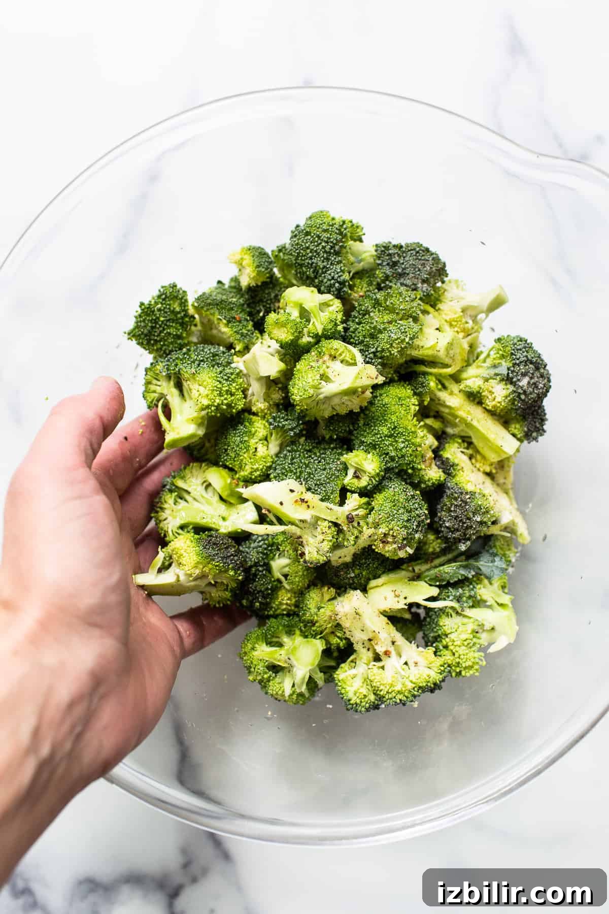 Broccoli florets in a bowl with seasoning.