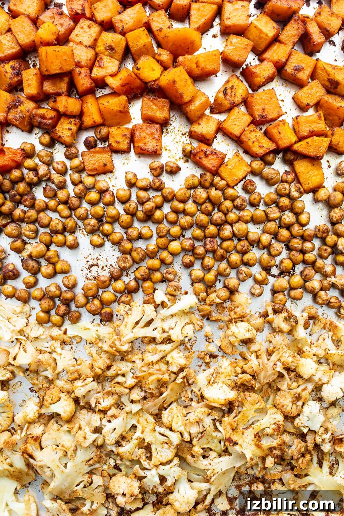 Butternut squash, chickpeas, and cauliflower on a baking sheet.