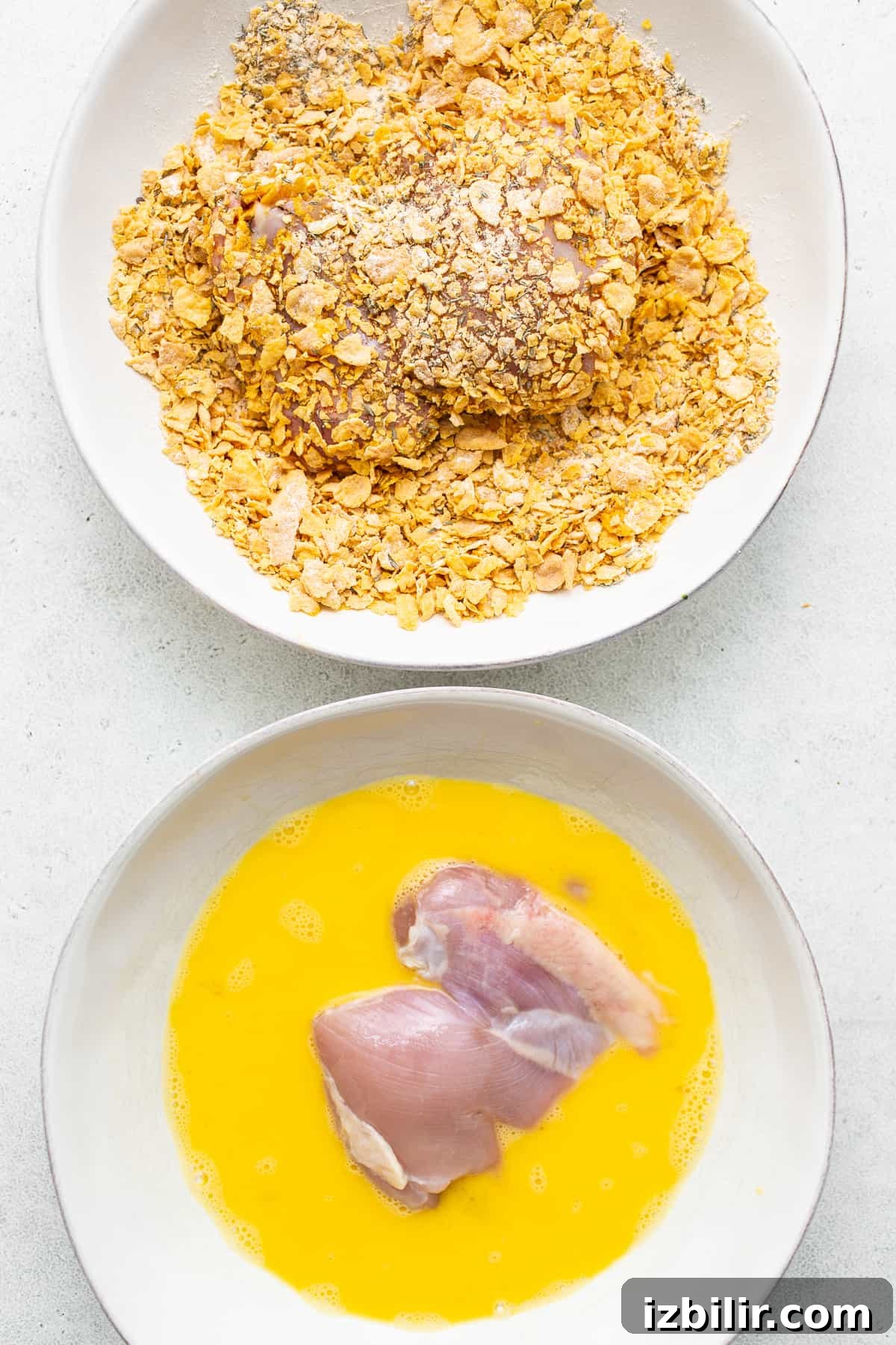 Chicken thighs being breaded.
