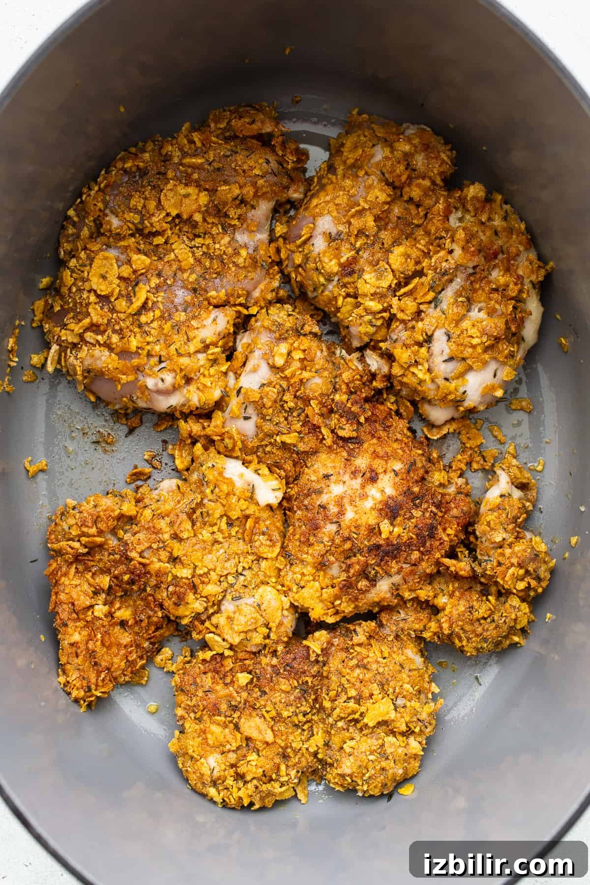 Breaded chicken being seared in a skillet.
