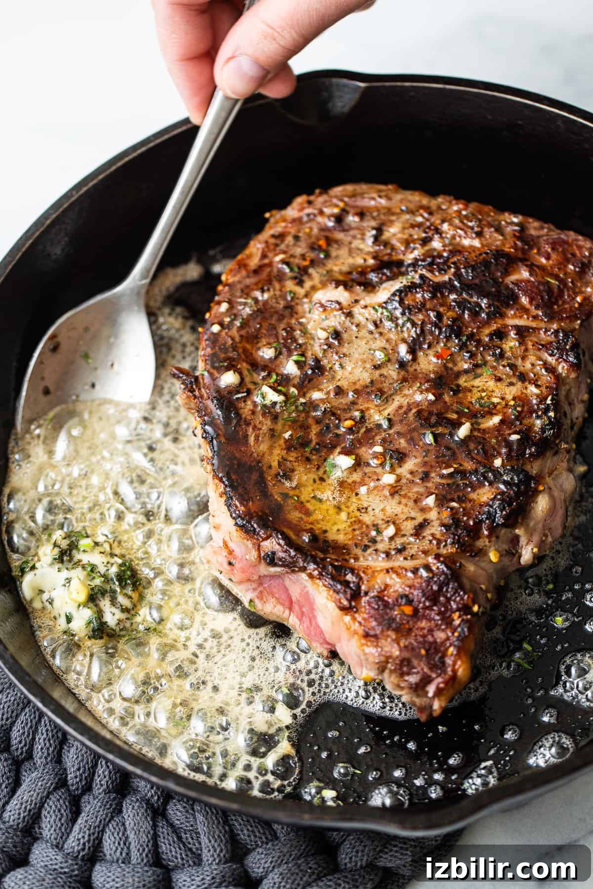 How to Make Restaurant-Style Cast Iron Steak at Home 6 A spoon scooping butter onto a steak.