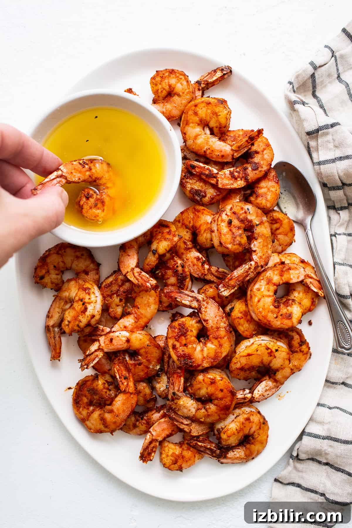 Broiled shrimp dipped in a bowl of honey butter sauce.