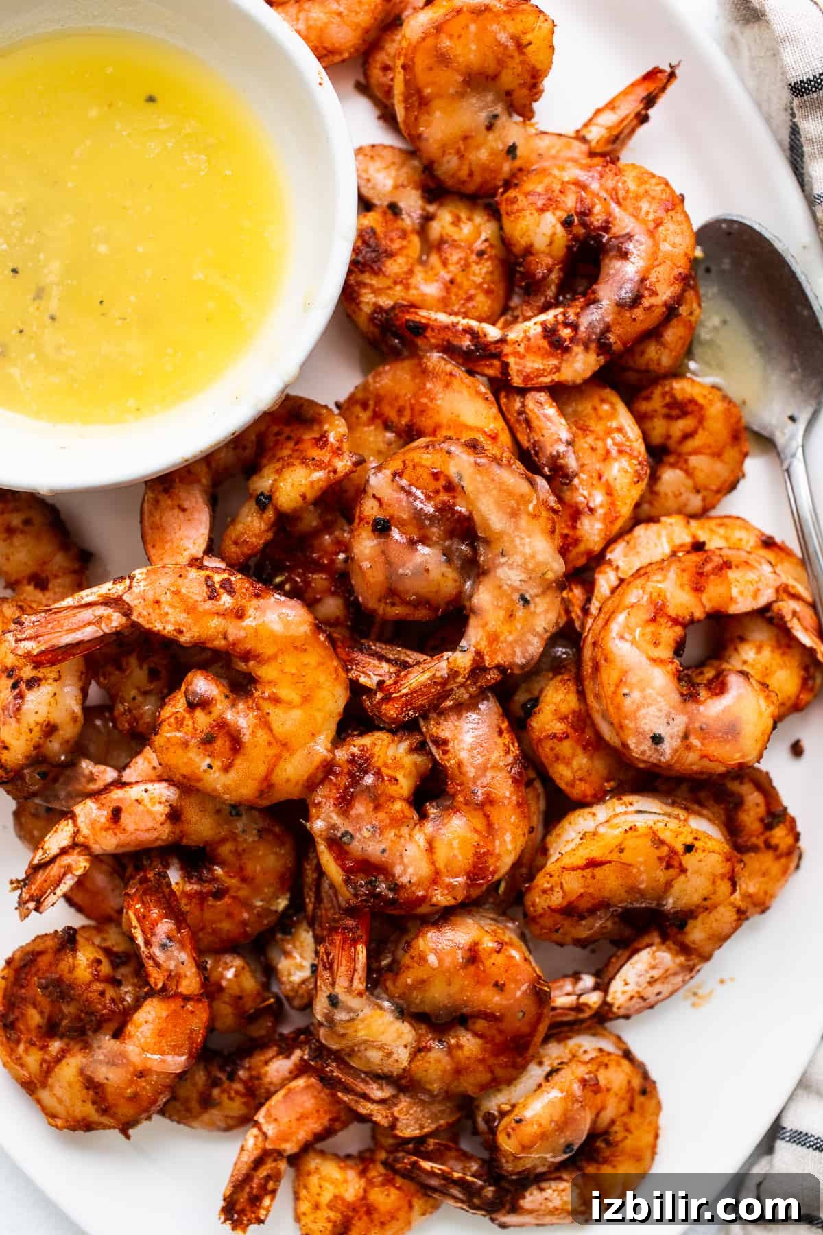 Broiled shrimp on a plate with a bowl of honey butter.