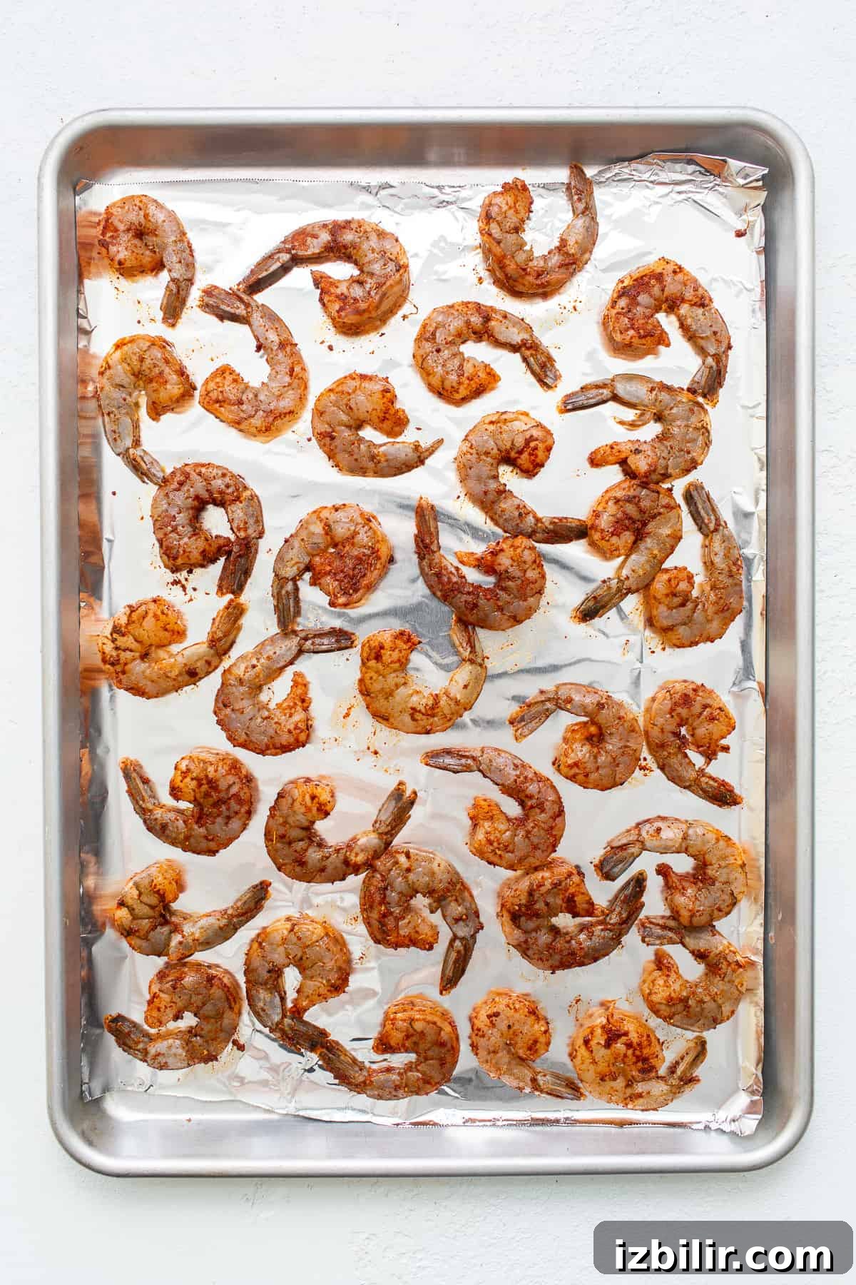 Seasoned shrimp on a baking sheet ready to be broiled.