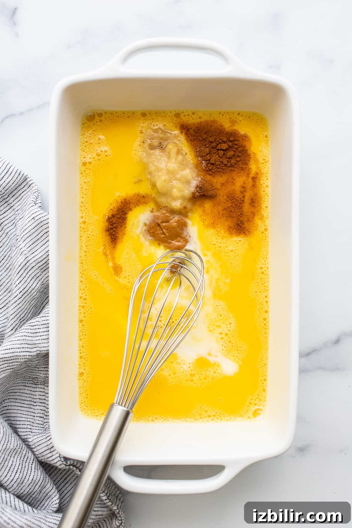 Egg wash for chunky monkey french toast in a bowl with a whisk.