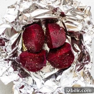Beets wrapped in foil on a white surface.
