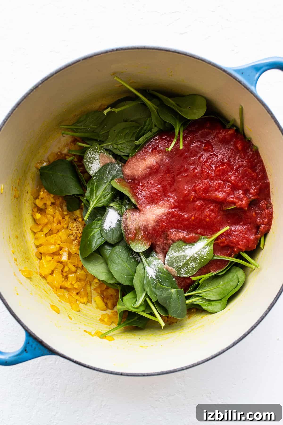 Spinach, crushed tomatoes and onions in a dutch oven.