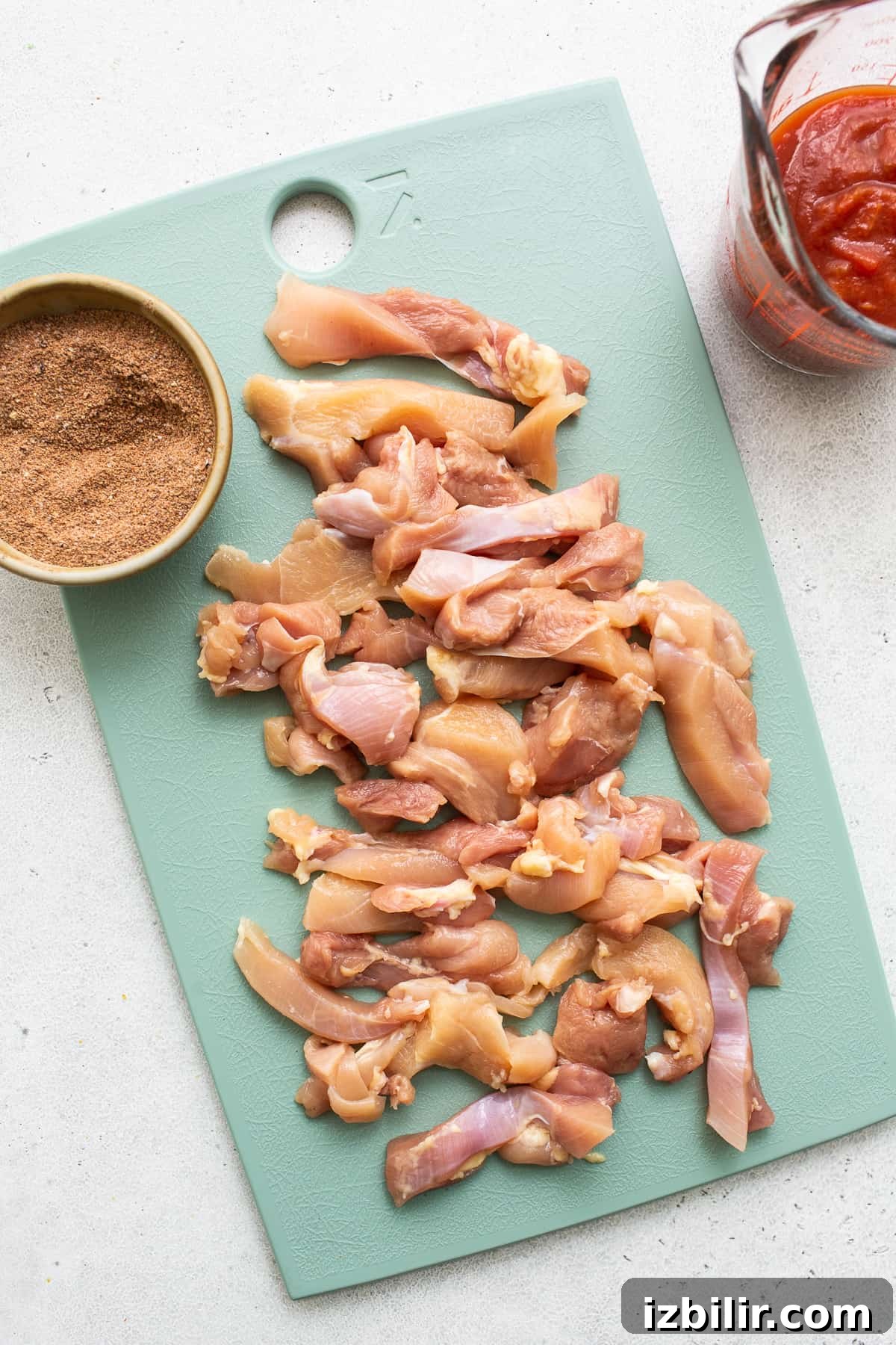 Sheet Pan Chicken Fajitas with less than 10 ingredients! This is made with chicken thighs, peppers and onions, and homemade fajita seasoning. chicken thighs on cutting board.