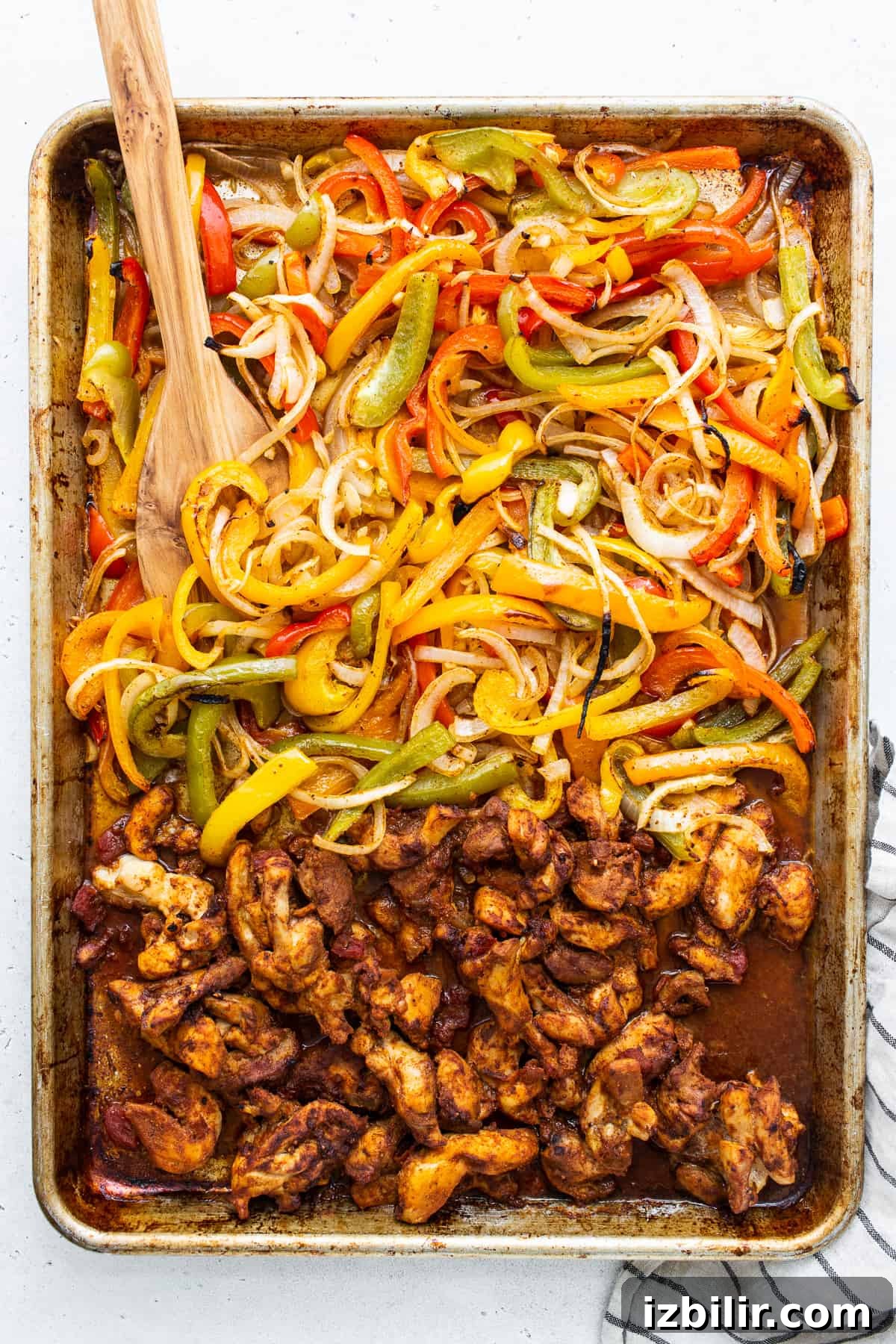 Sheet Pan Chicken Fajitas with less than 10 ingredients! This is made with chicken thighs, peppers and onions, and homemade fajita seasoning. sheet pan chicken fajitas on baking sheet.