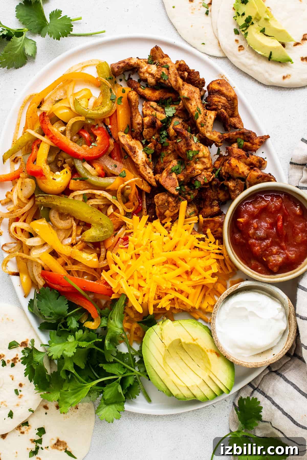 Sheet Pan Chicken Fajitas with less than 10 ingredients! This is made with chicken thighs, peppers and onions, and homemade fajita seasoning. chicken fajitas on platter.