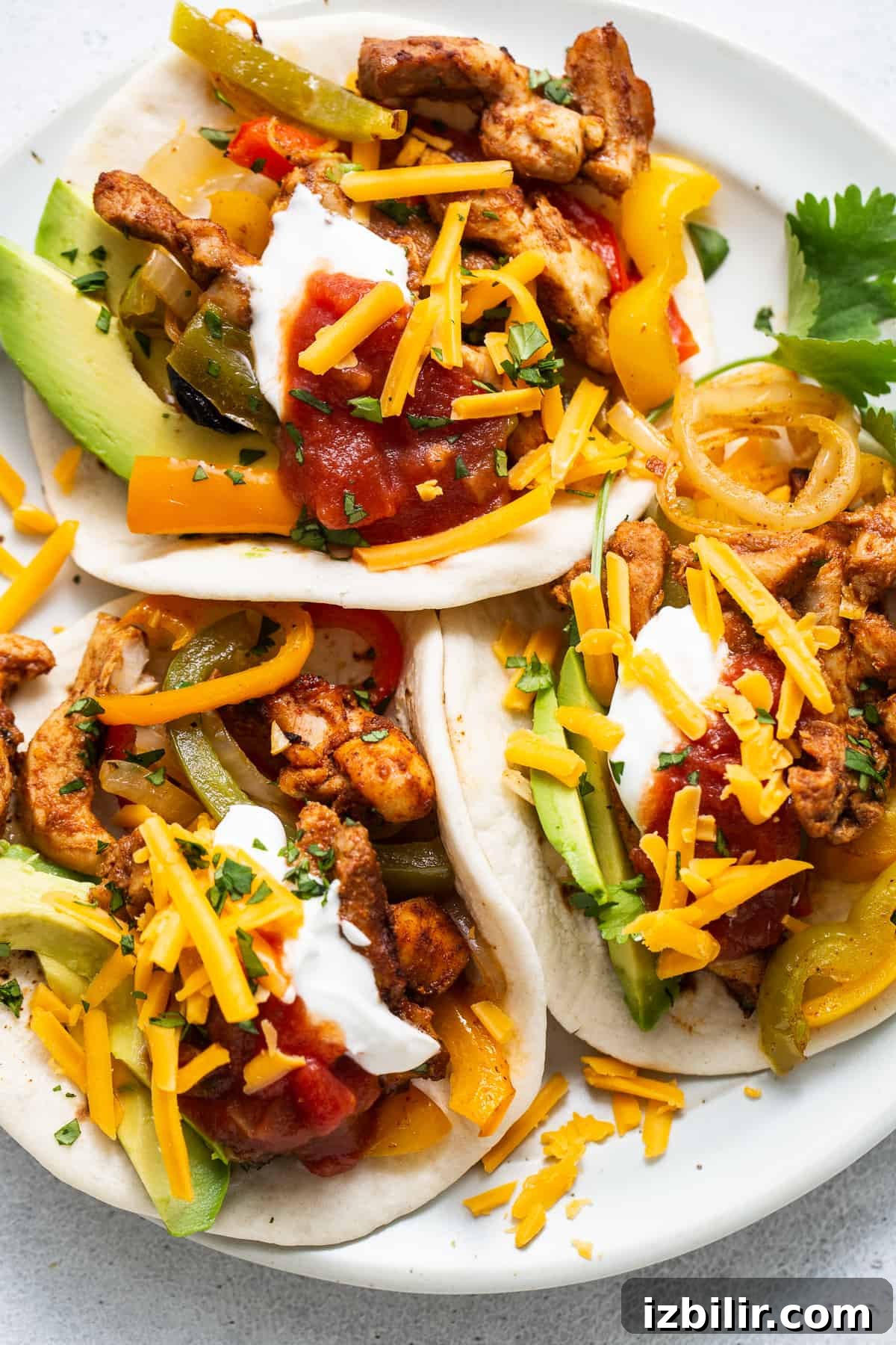 Sheet Pan Chicken Fajitas with less than 10 ingredients! This is made with chicken thighs, peppers and onions, and homemade fajita seasoning. fajita on plate.
