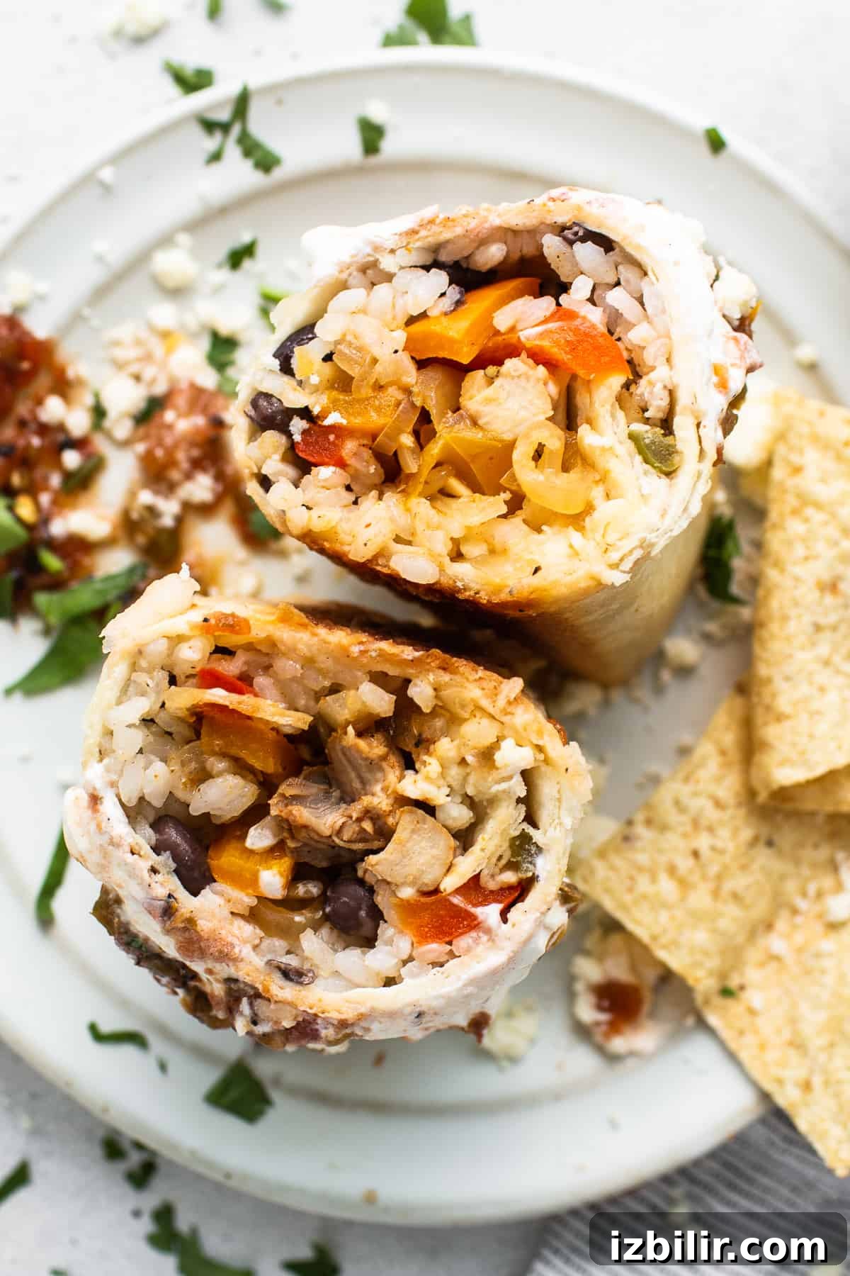 Chicken Fajita Burrito Recipe with Peppers and Onions 8 Chicken fajita burrito cut in half on a plate.