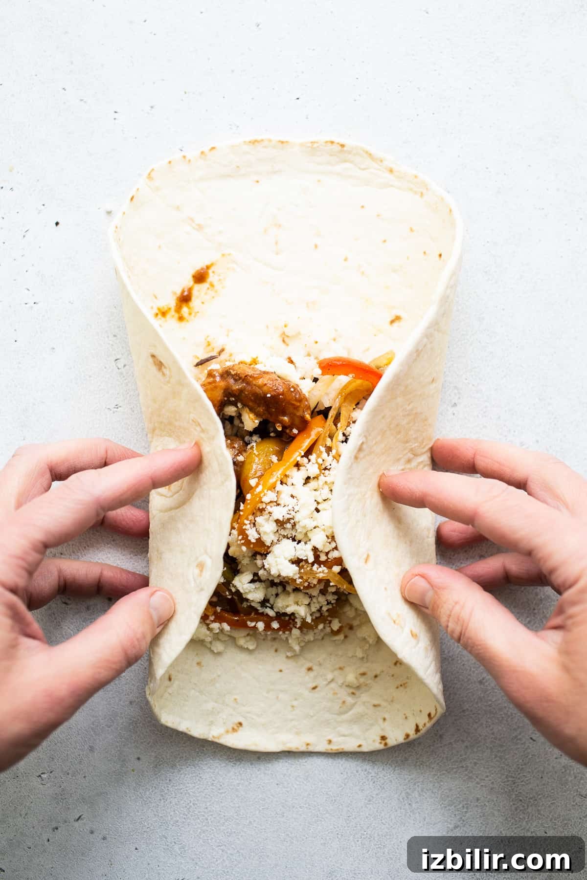 Chicken Fajita Burrito Recipe with Peppers and Onions 5 Chicken fajita burrito being rolled up.