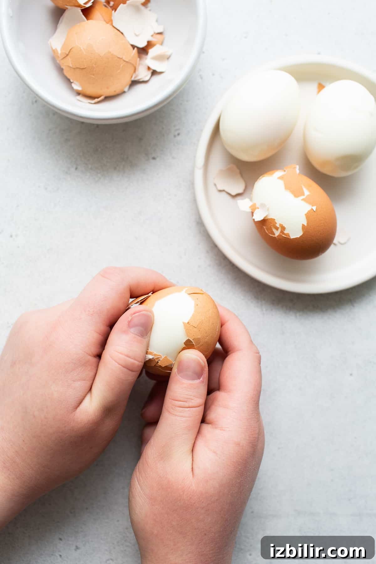 Hands peeling hard boiled eggs.