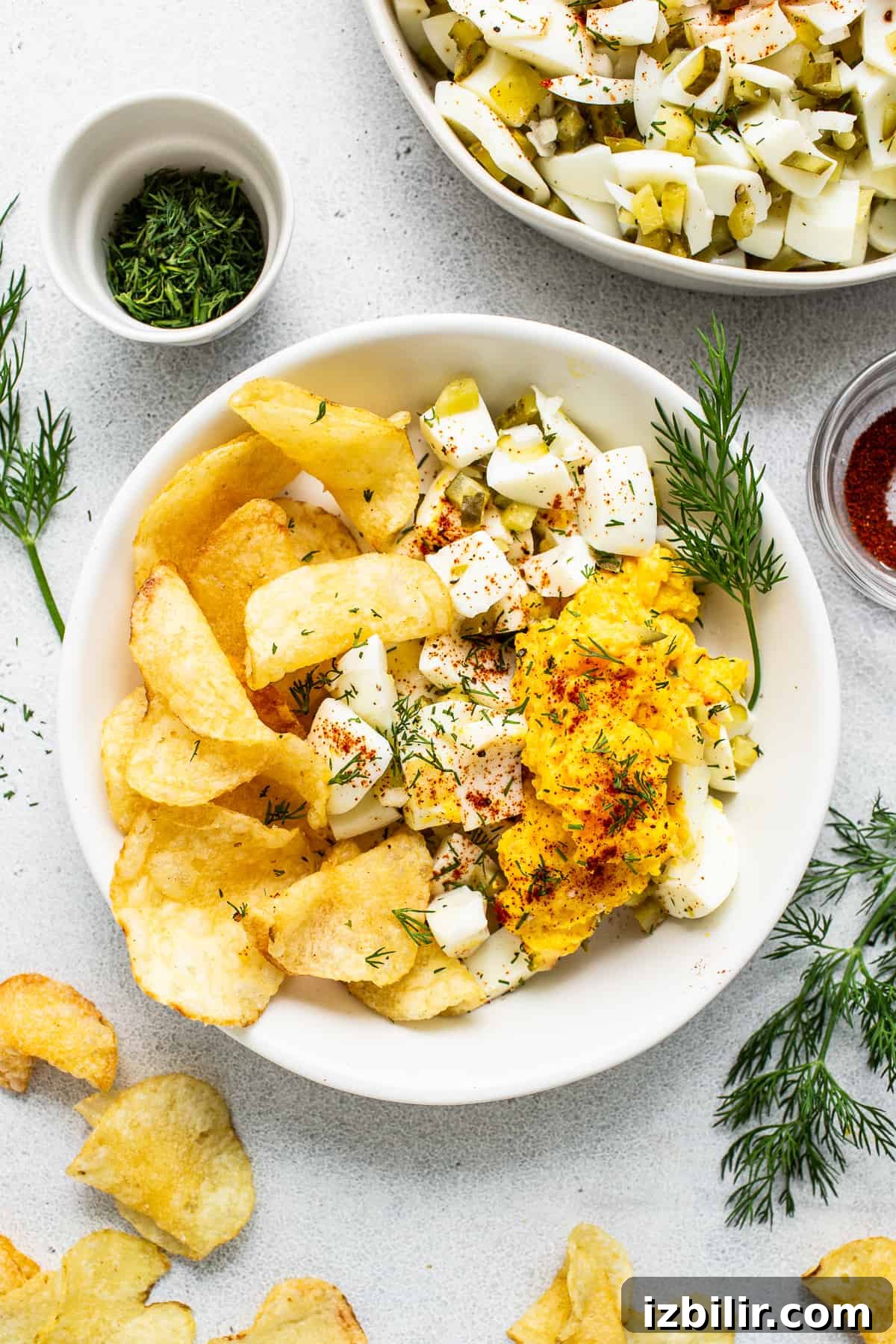 Deviled egg salad in a bowl with potato chips.