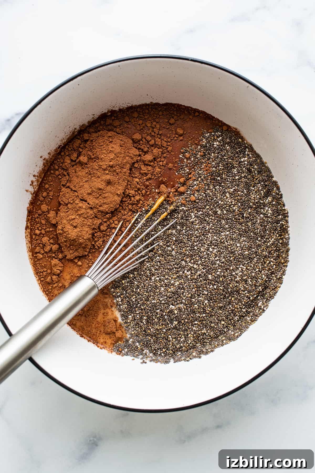 Chia seeds and cocoa powder in a bowl with a whisk.