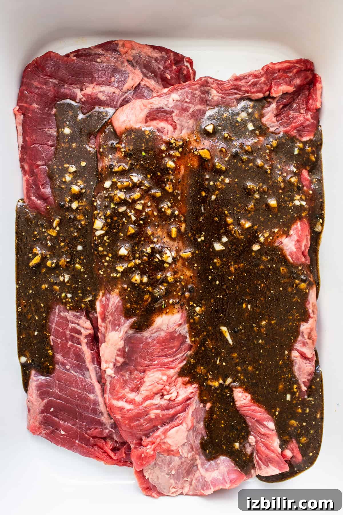 Skirt steak marinating in a pan.