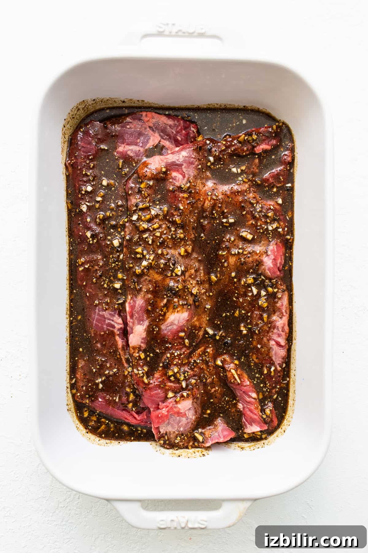 Skirt steak marinating in a baking dish.